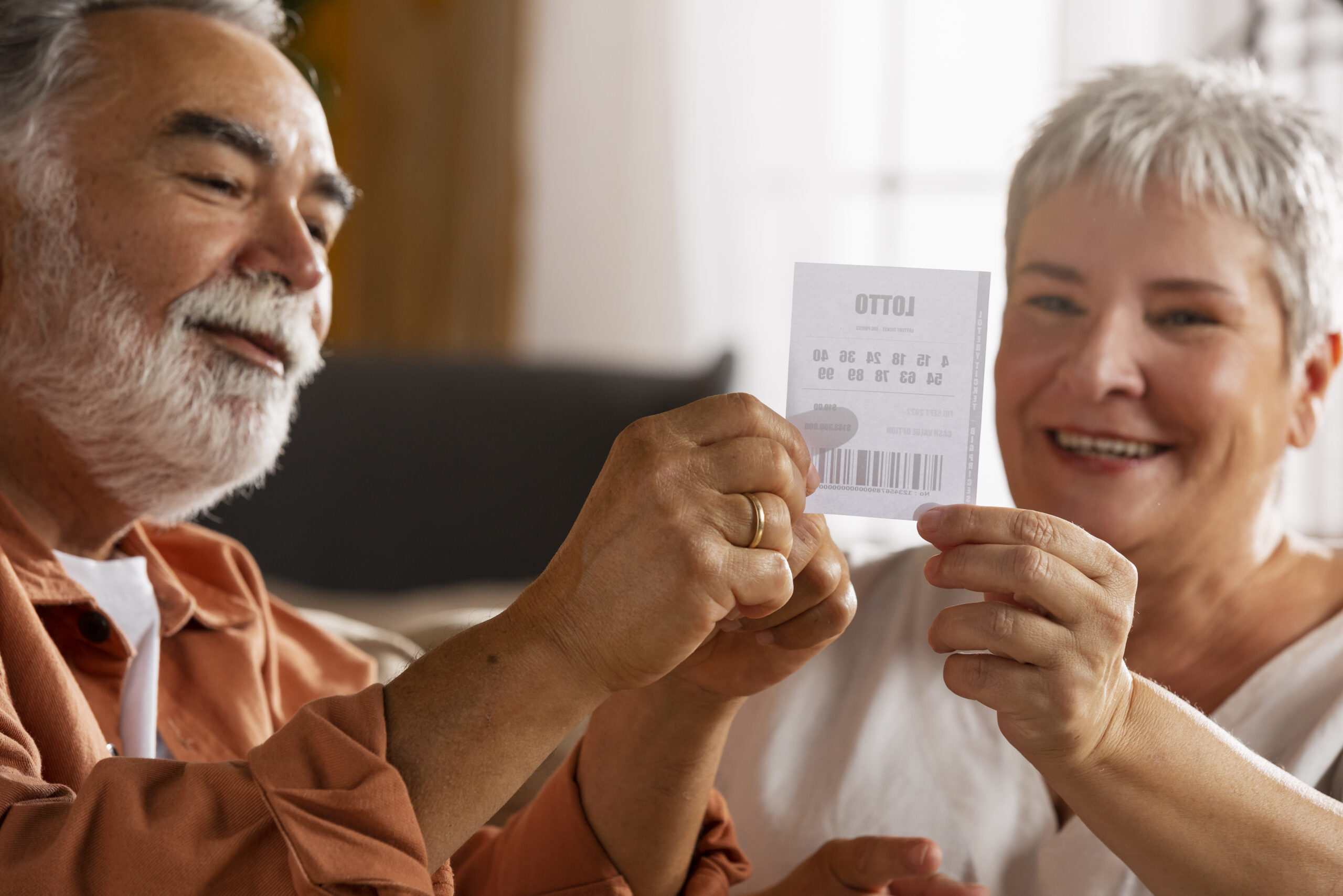 Couple holding up and staring at a lottery ticket, smiling.